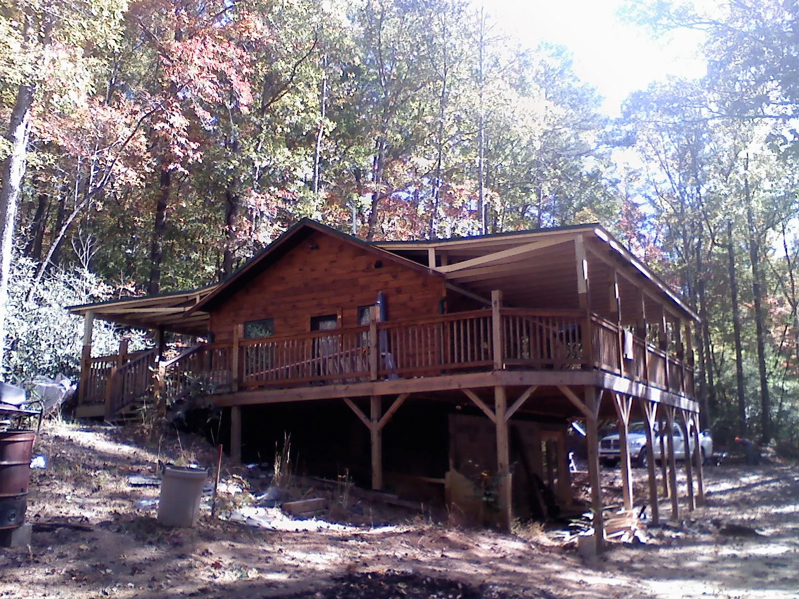 Log cabin with a wraparound porch and metal roof in the fall in Merrittstown