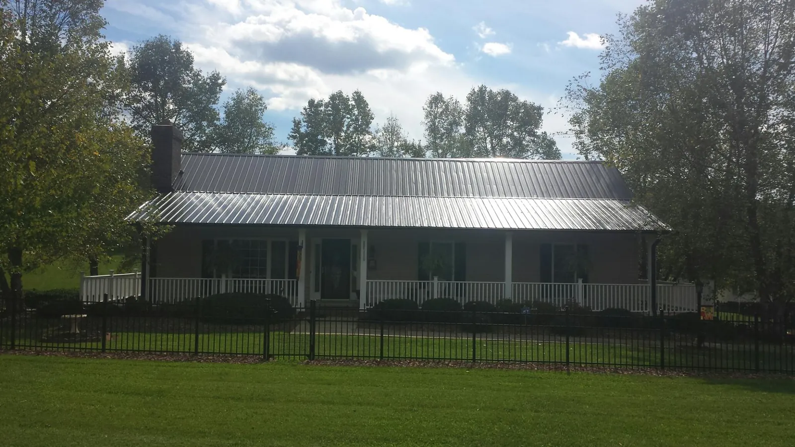 Gray metal roof on a brick ranch with a full width front porch — Gutter Guard Installation work by our crew in Merrittstown