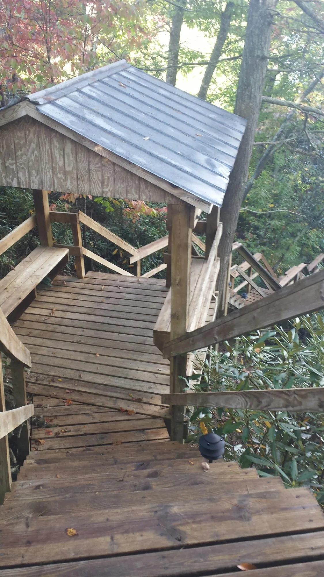 Metal roofed shelter over wooden steps on a wooded walkway — Skylight Repair & Installation work by our crew in Merrittstown