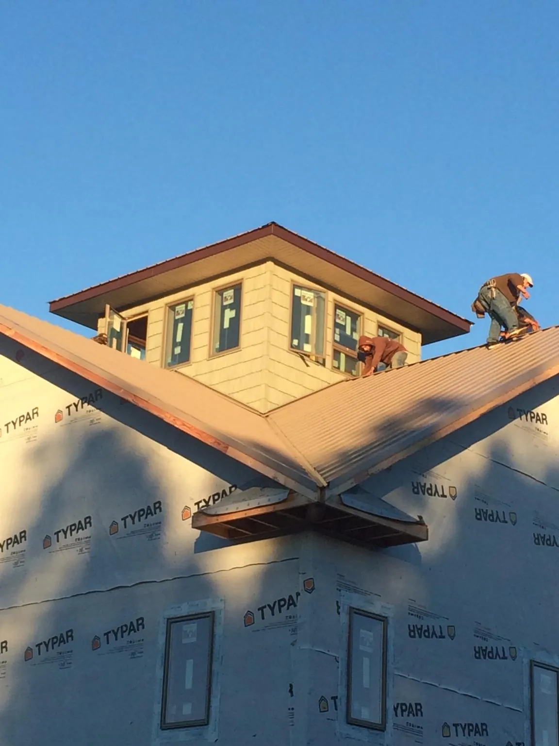 Roofers working around a rooftop cupola on a new metal roof at sunset — Roof Waterproofing in Merrittstown by Roofing Brothers